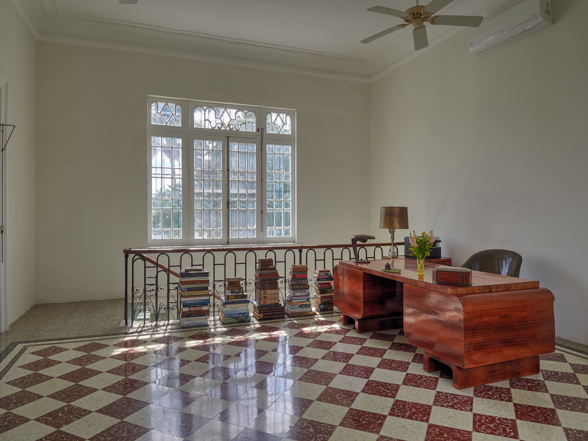 Sunlit room with checkered floor and vintage wooden furniture.