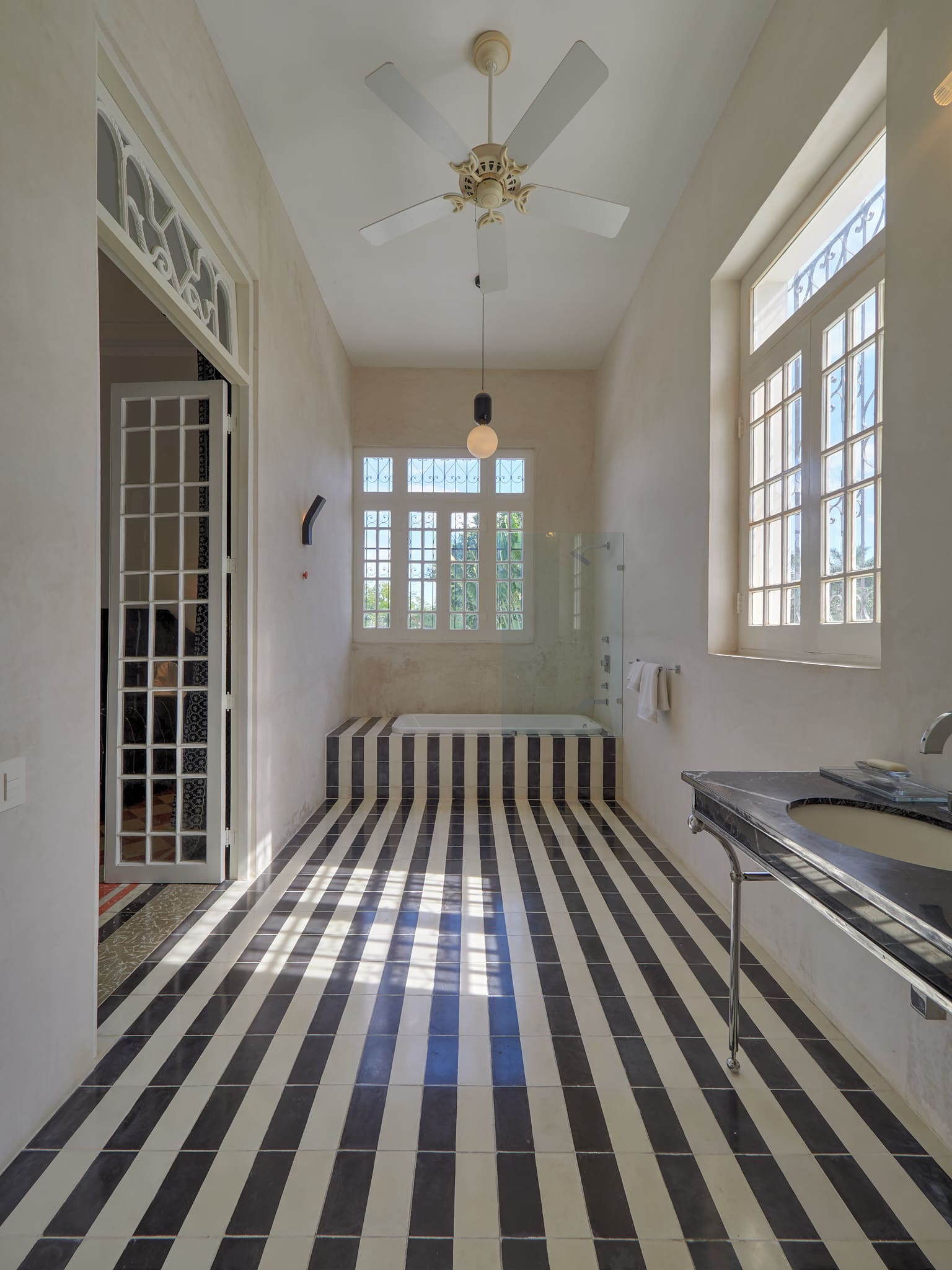 Sunlit room with black and white striped floor tiles and large windows.