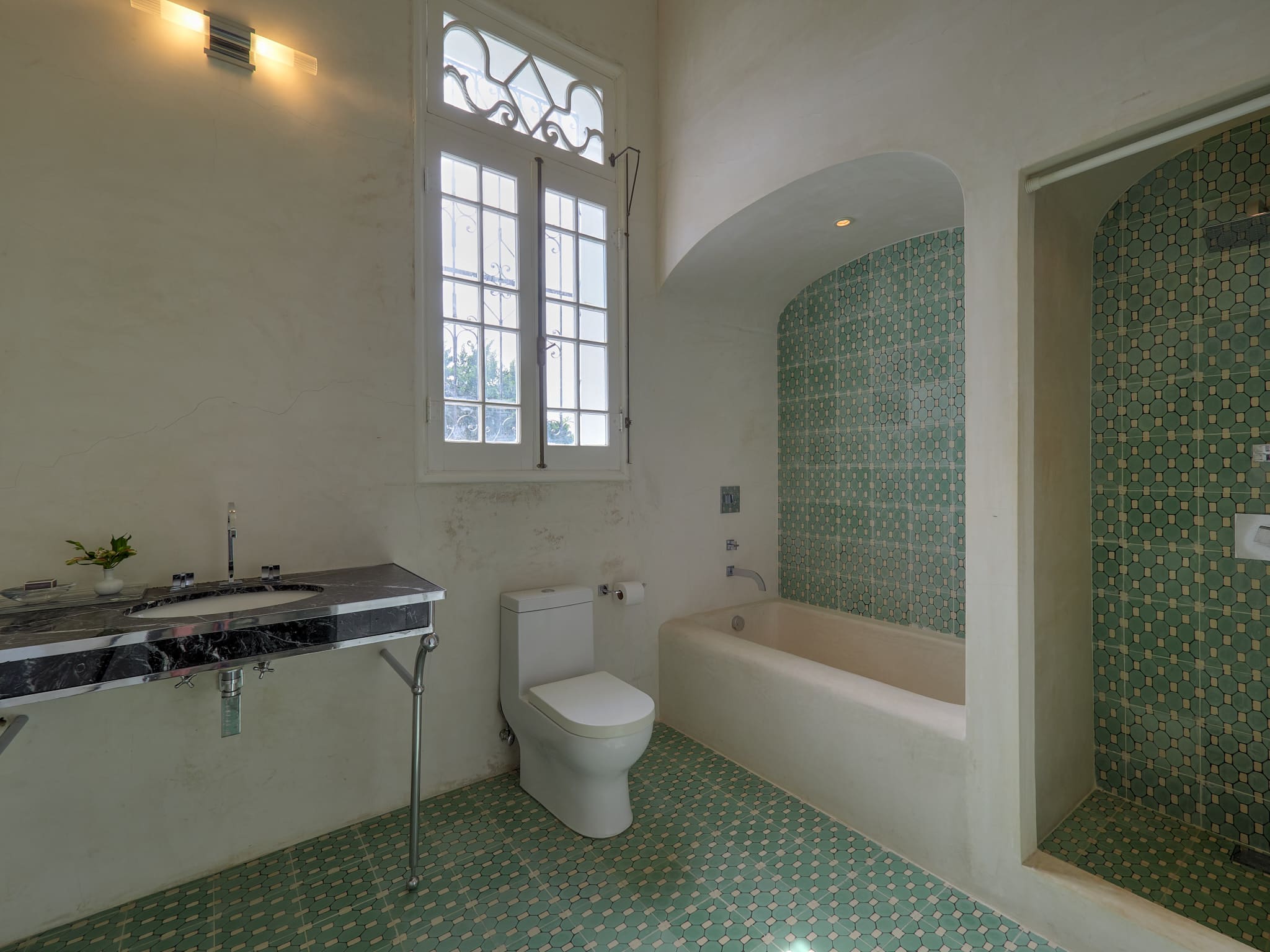 Bright bathroom with green tile floor and bathtub.