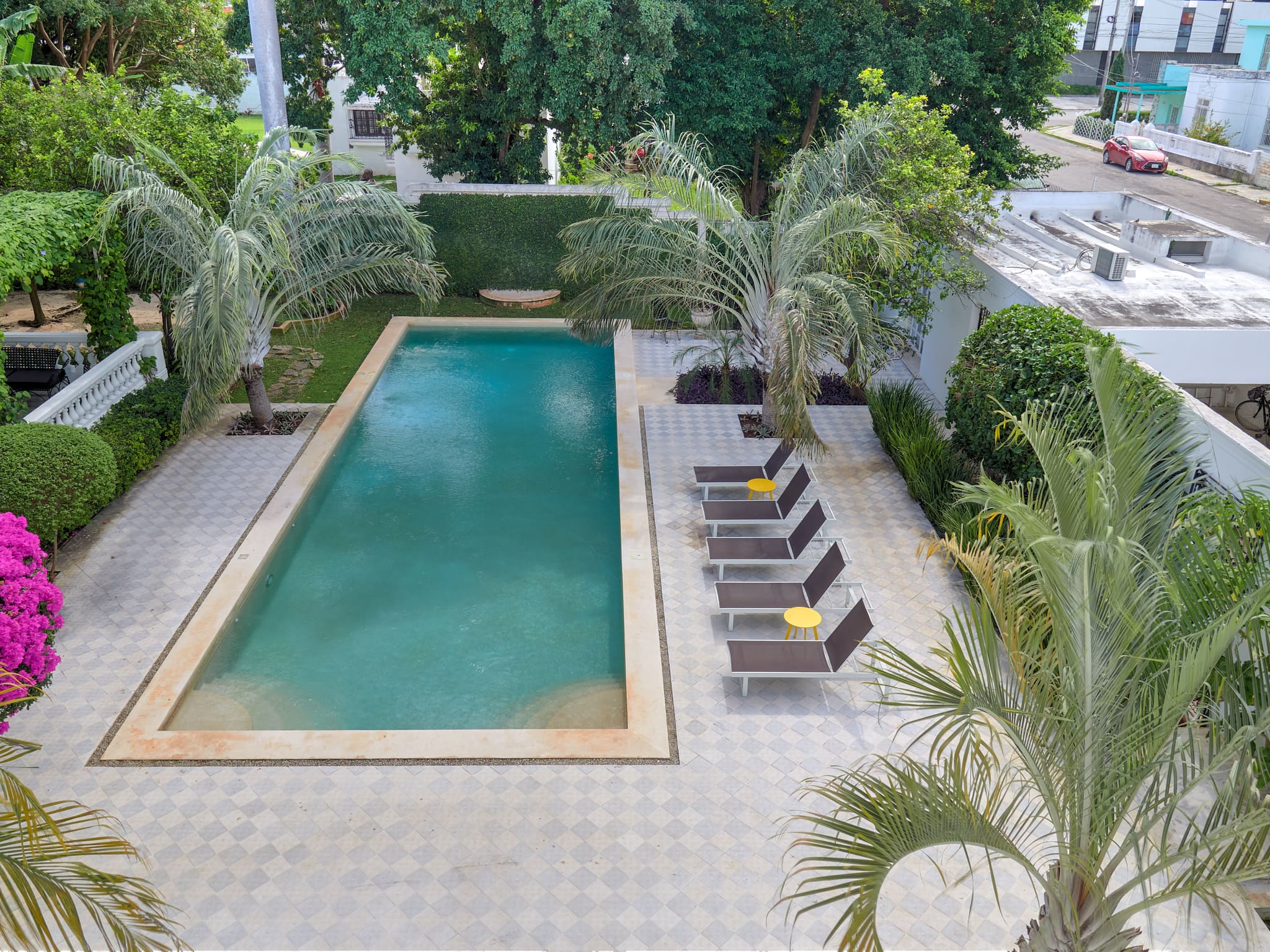 A serene outdoor pool surrounded by lounge chairs and lush greenery.