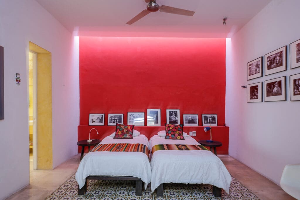 Cozy bedroom with twin beds and vibrant red accent wall lighting.