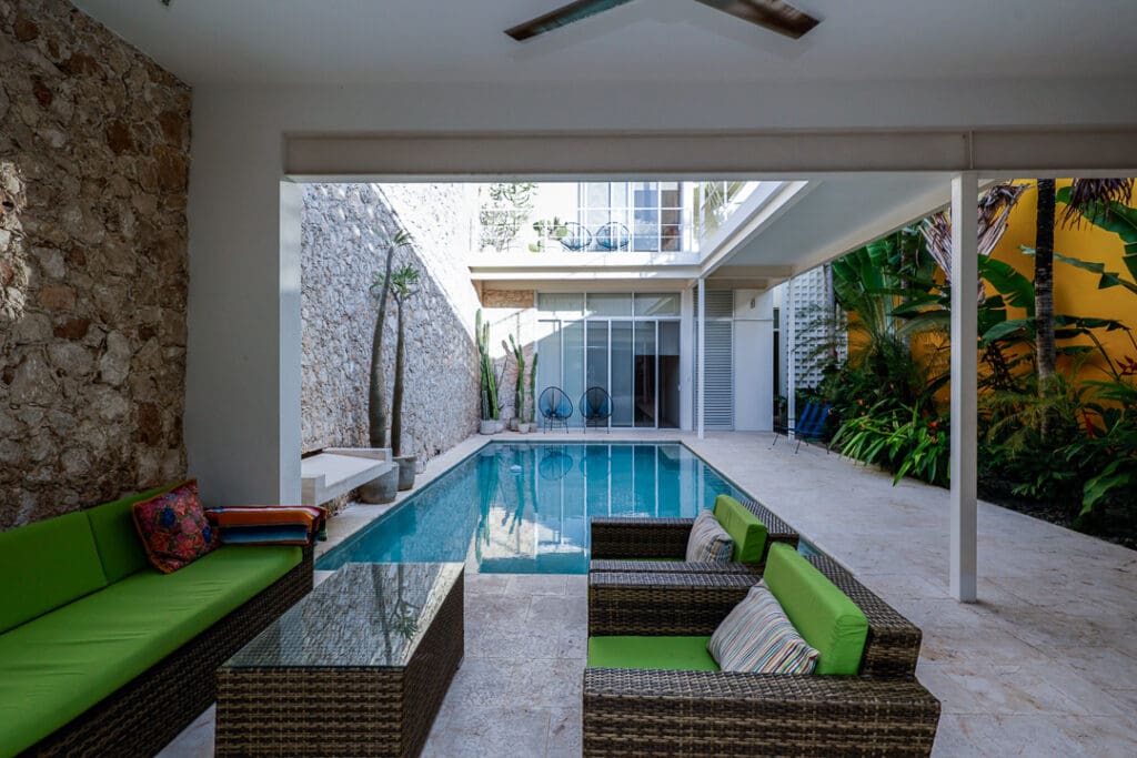 Modern indoor pool area with glass ceiling and cozy seating.