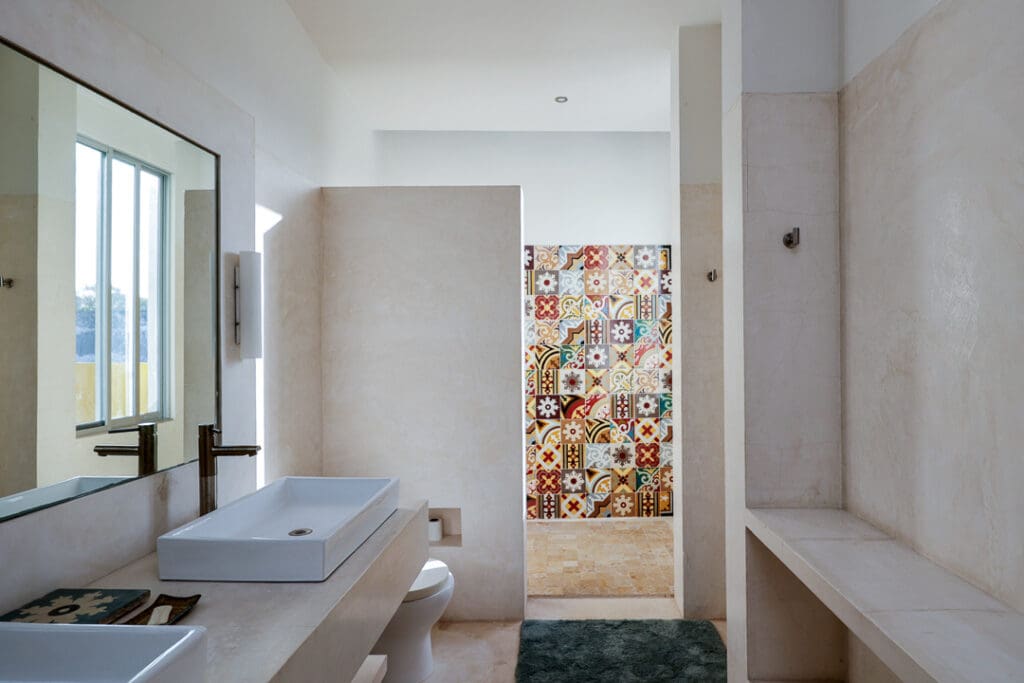 Minimalist bathroom with colorful tiled shower area and white fixtures.