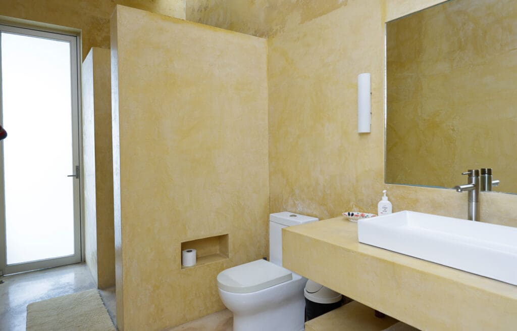 Minimalist beige bathroom with a toilet and sink.