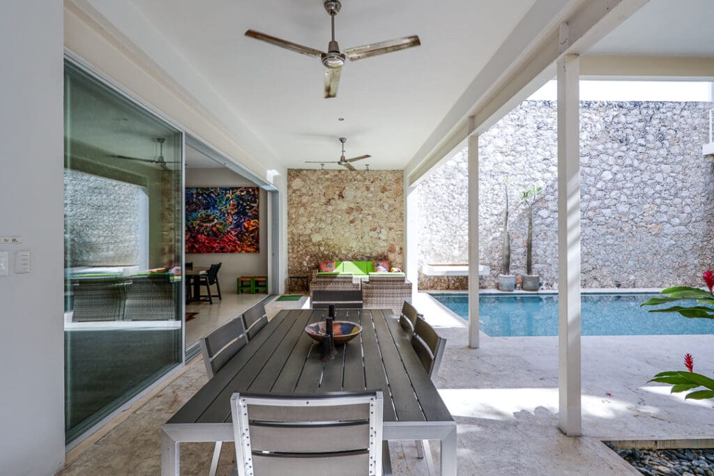 Modern outdoor dining area with ceiling fans and a pool.
