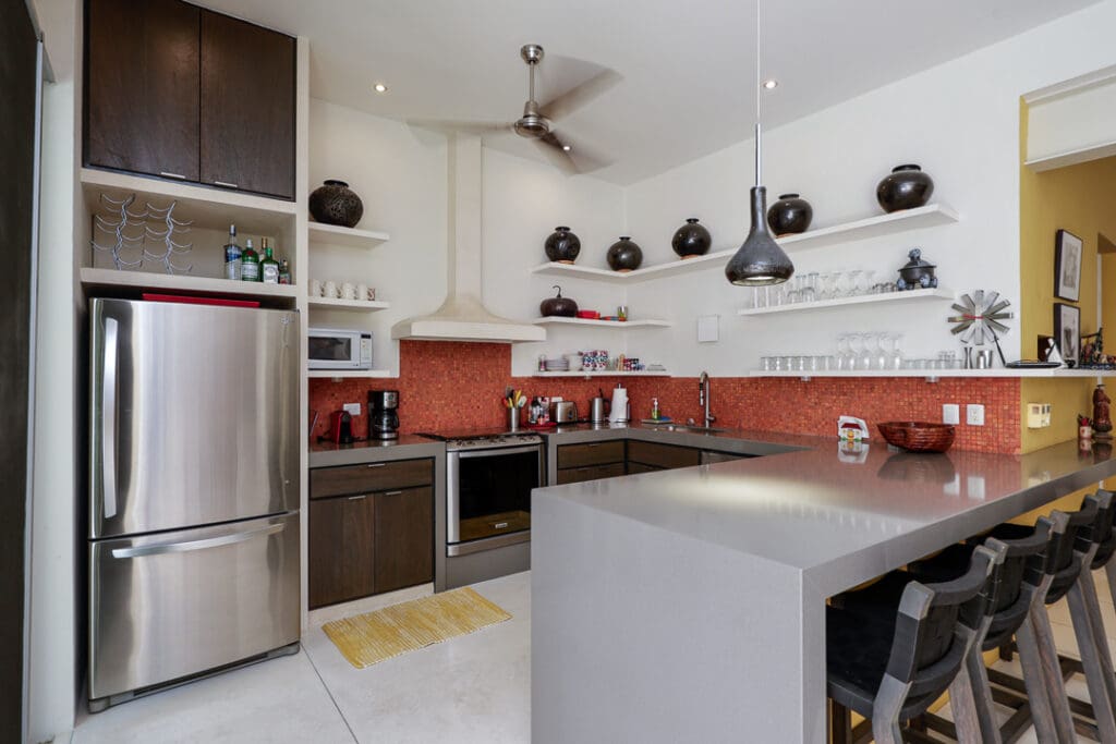 Modern kitchen with sleek cabinetry and red backsplash.