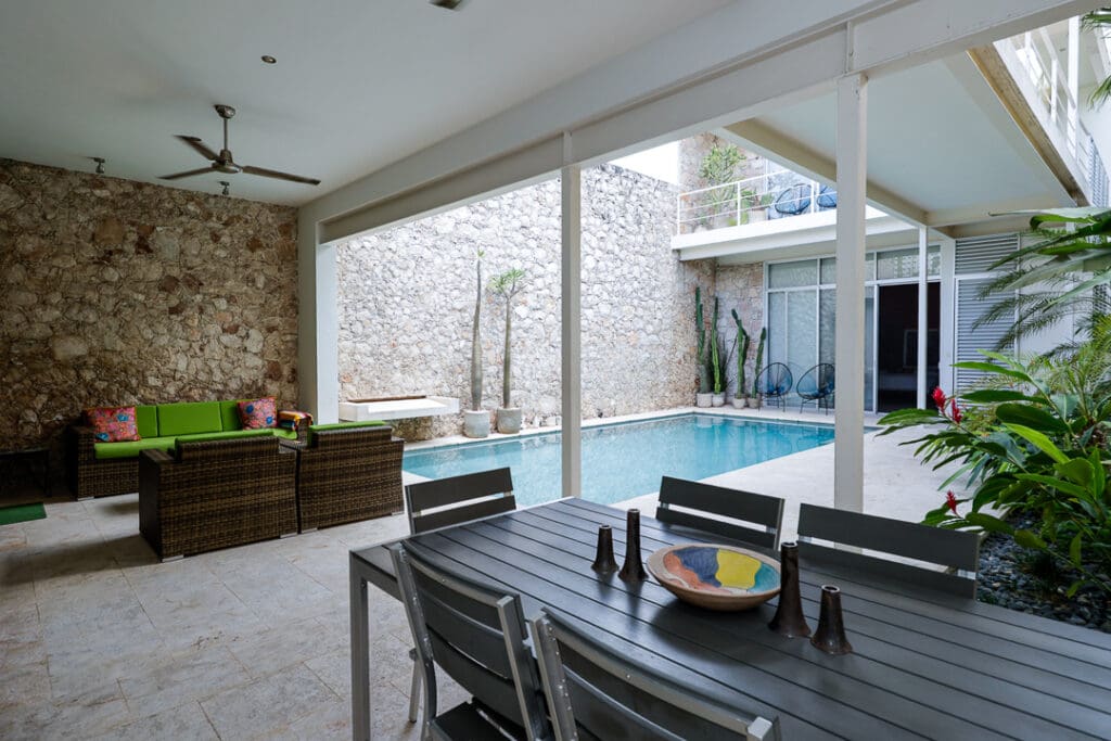 Modern outdoor patio with dining area and pool under a covered space.