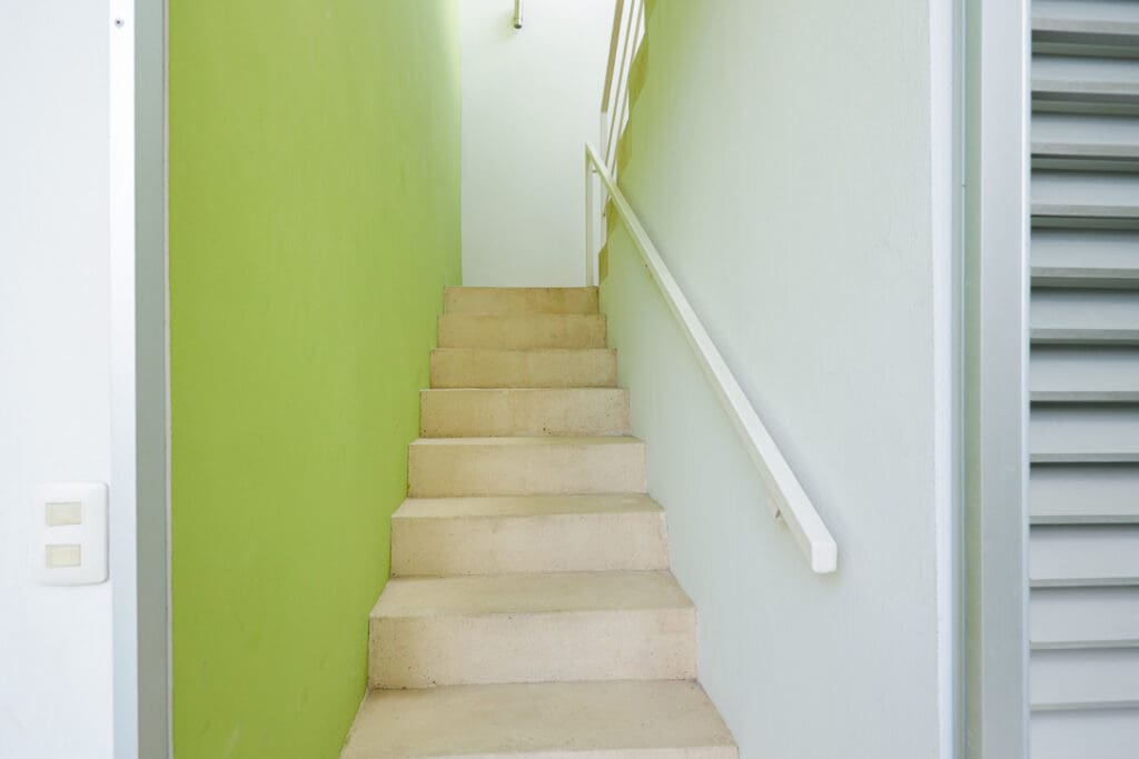 Narrow staircase with green and white walls and handrails.