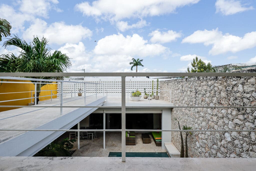 Modern house with stone walls and a flat roof under a blue sky.