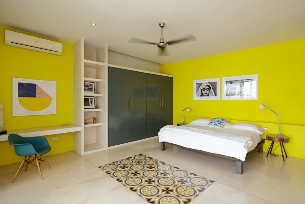 Modern bedroom with bright yellow walls and minimalist decor.