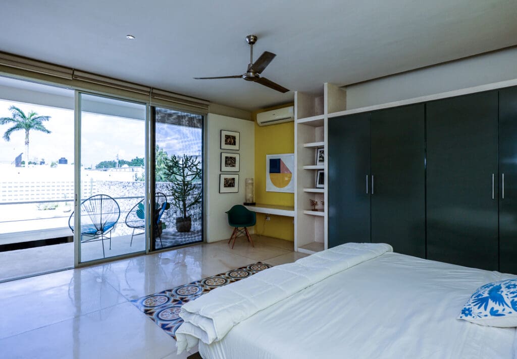Modern bedroom with balcony overlooking a pool and ocean view.