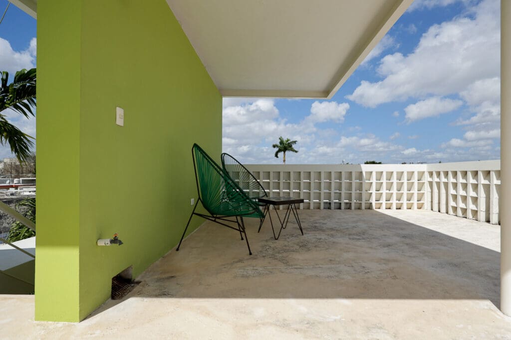 Modern balcony with green chairs and a palm tree view.