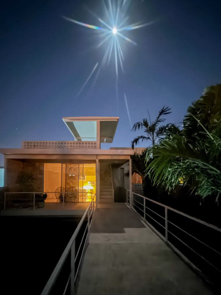 Modern house illuminated under a starry night sky.