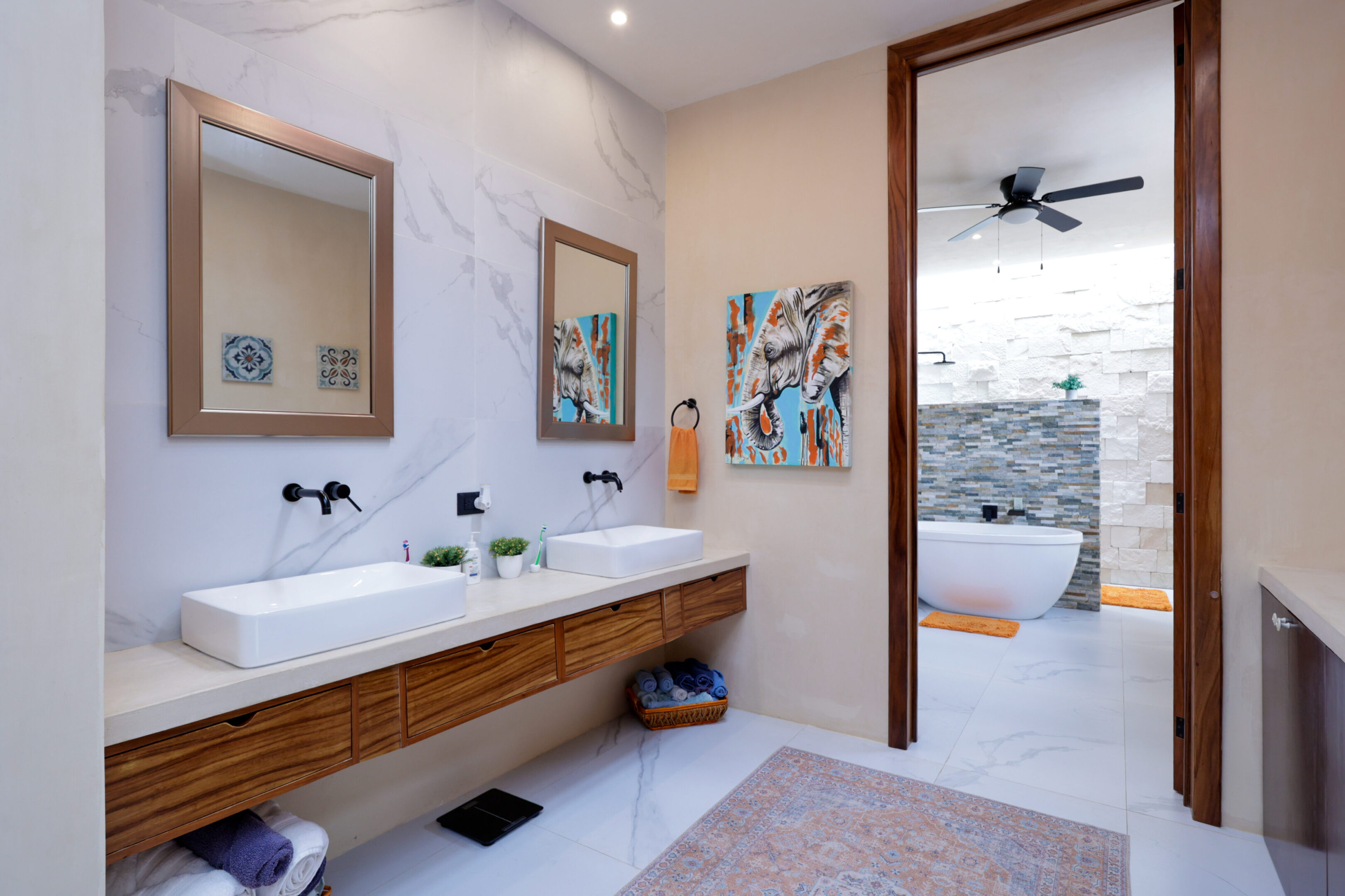 Modern bathroom with wooden vanity and art pieces.