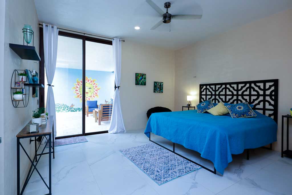 Bright bedroom with blue bedding and balcony view.