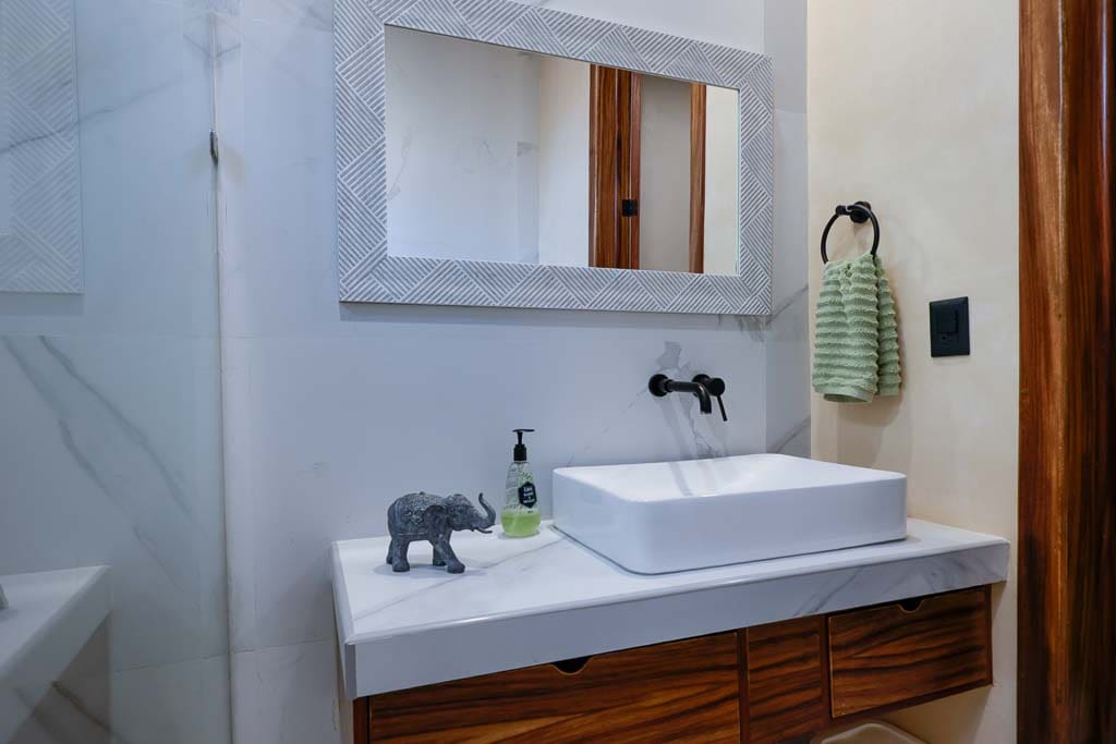 Modern bathroom sink with wooden cabinet and elephant decor.