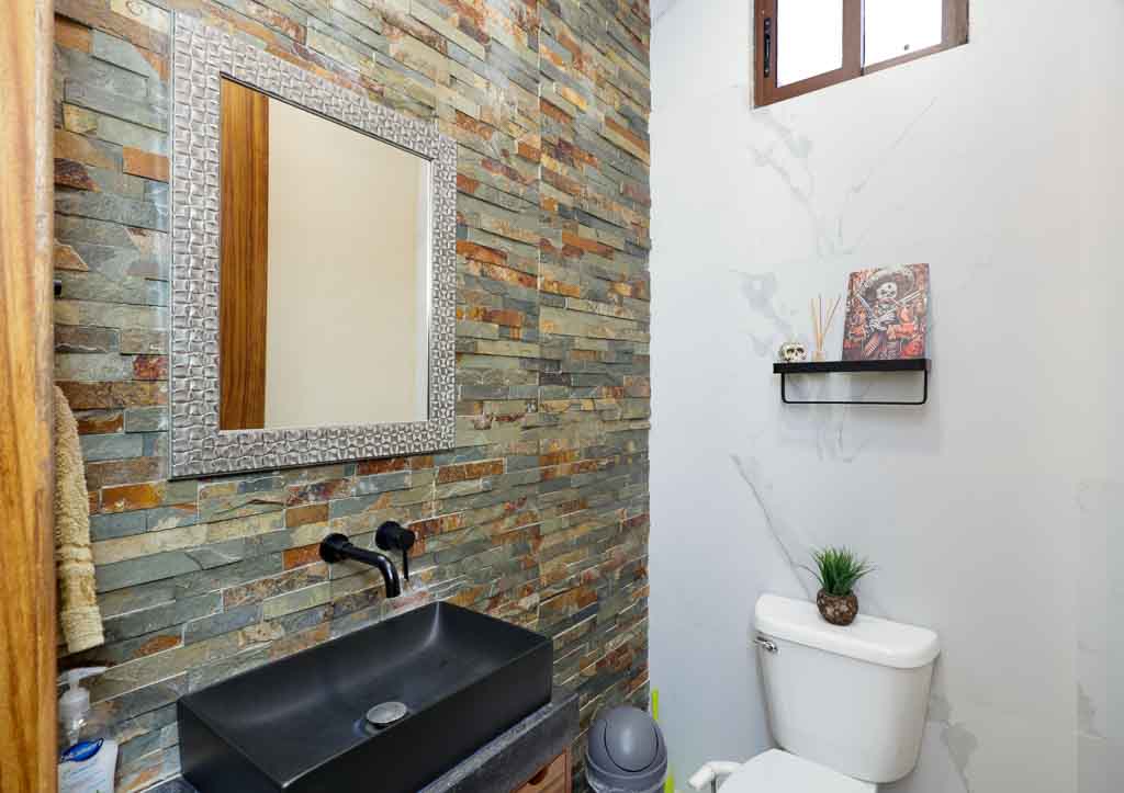 Modern bathroom with stone accent wall and sleek black sink.