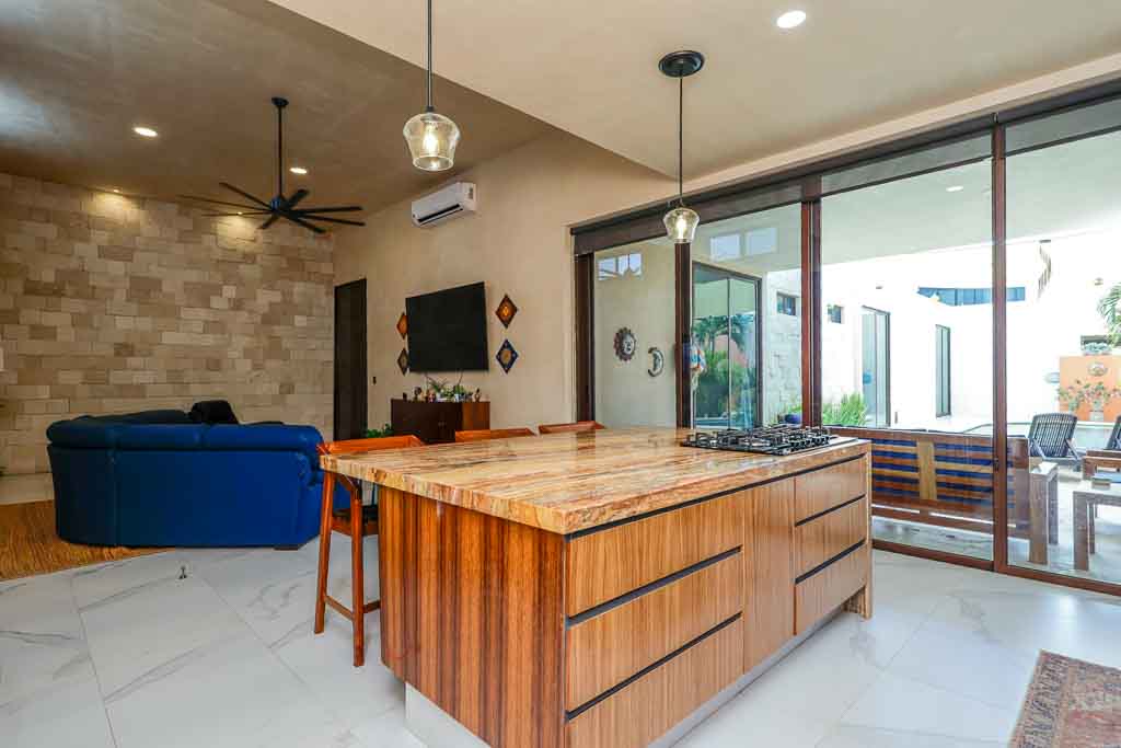 Modern kitchen with wooden island and large glass doors.