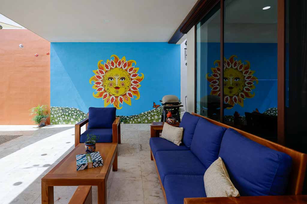 Cozy patio with blue sofa and colorful sun wall art.