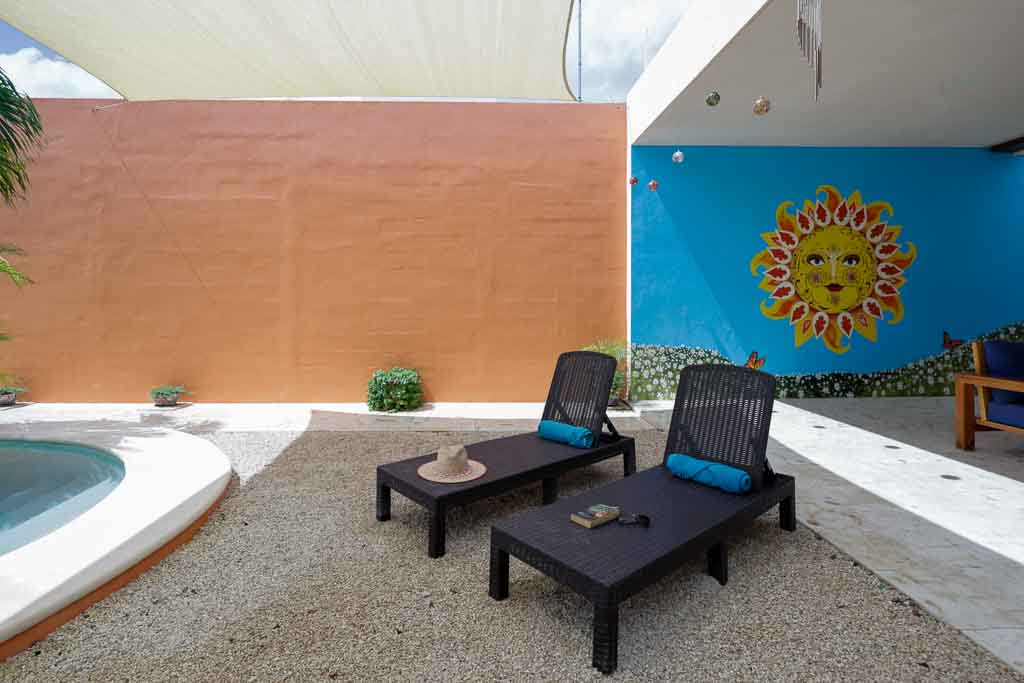 Outdoor lounge area with two black chairs and a small table on gravel.
