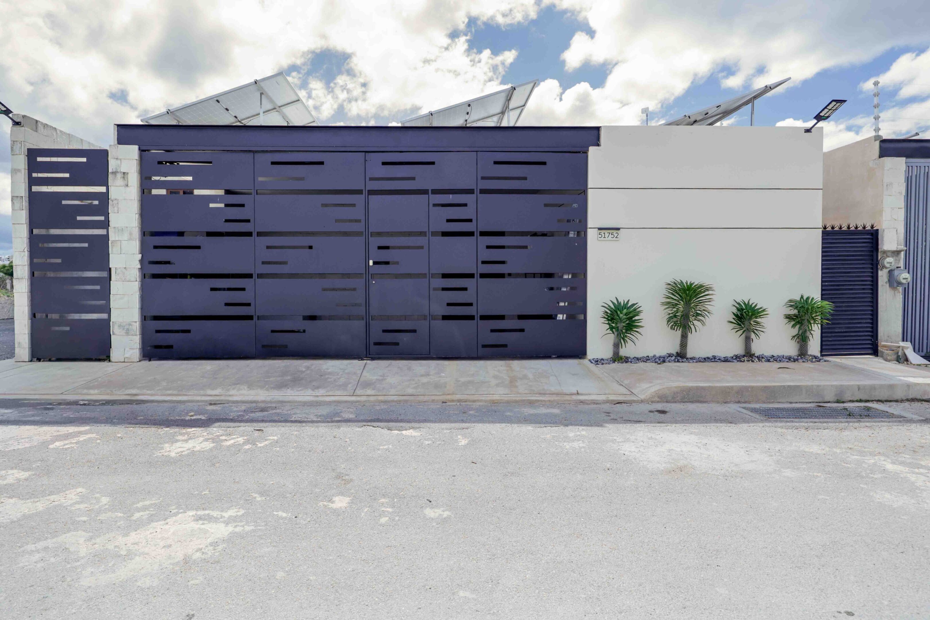 Modern blue garage door with a white wall and small plants.