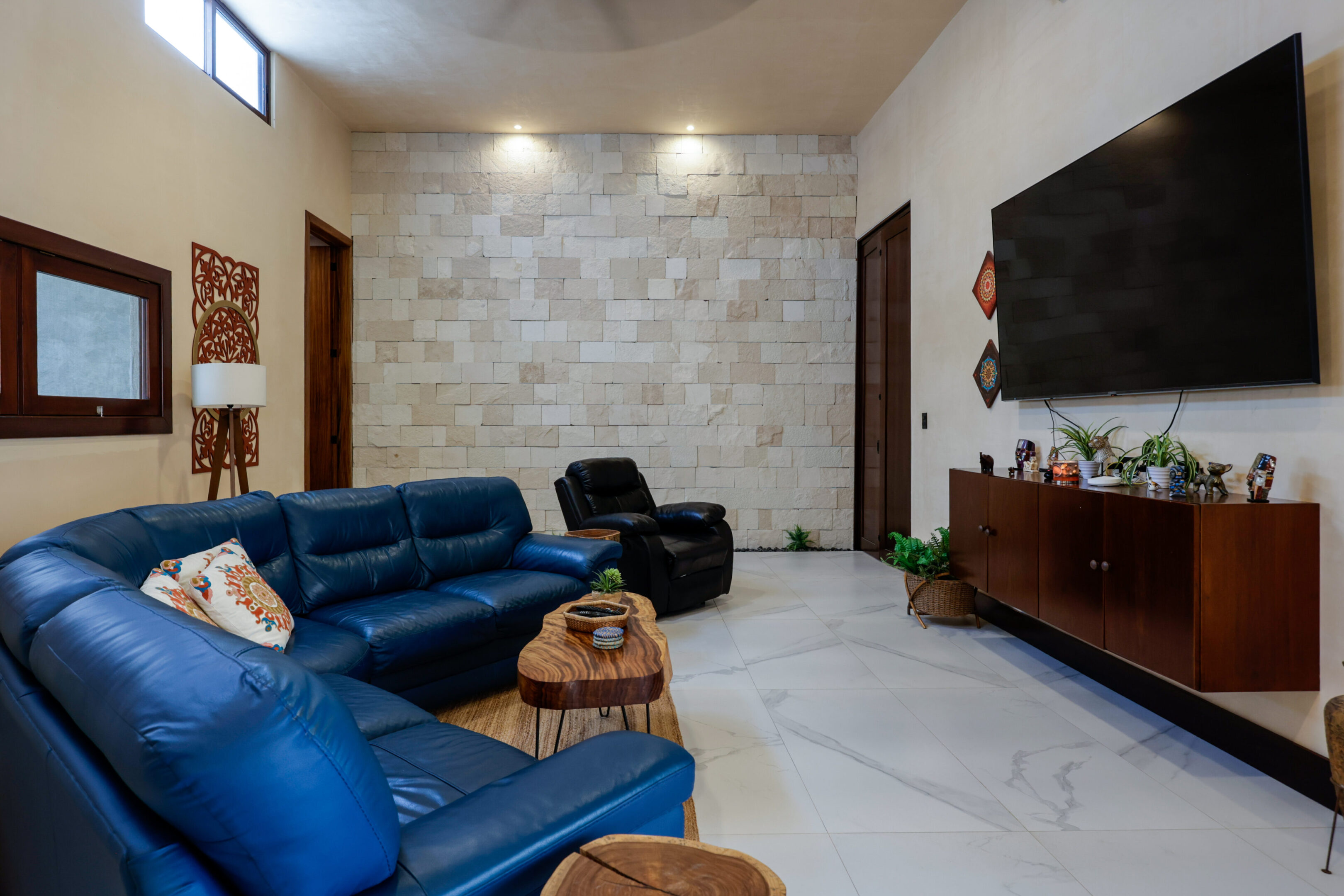 Modern living room with blue sofas and stone accent wall.