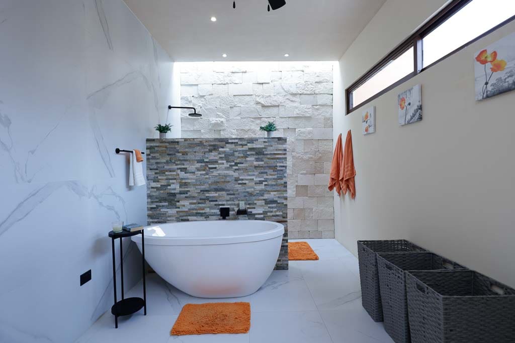 Modern bathroom with freestanding tub and orange accents.