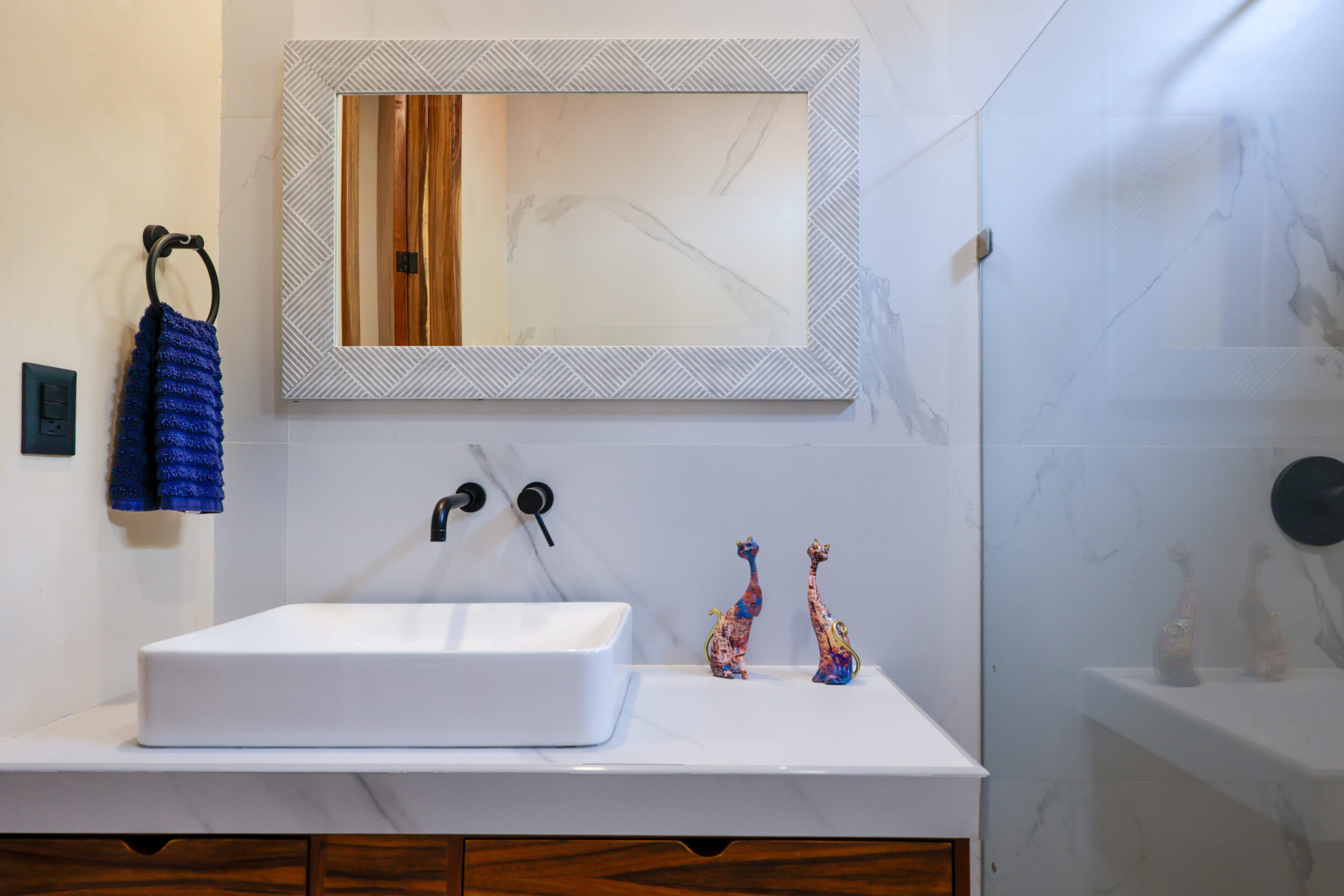 Minimalist bathroom sink area with a rectangular mirror and modern fixtures.