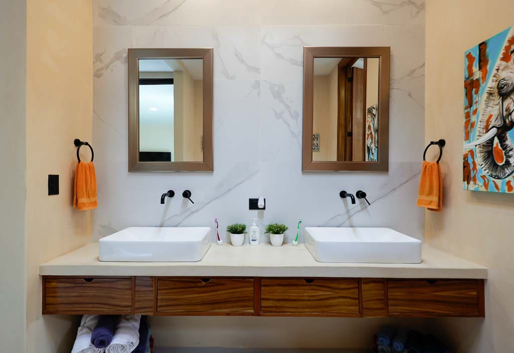 Modern bathroom with dual sinks and wooden accents.