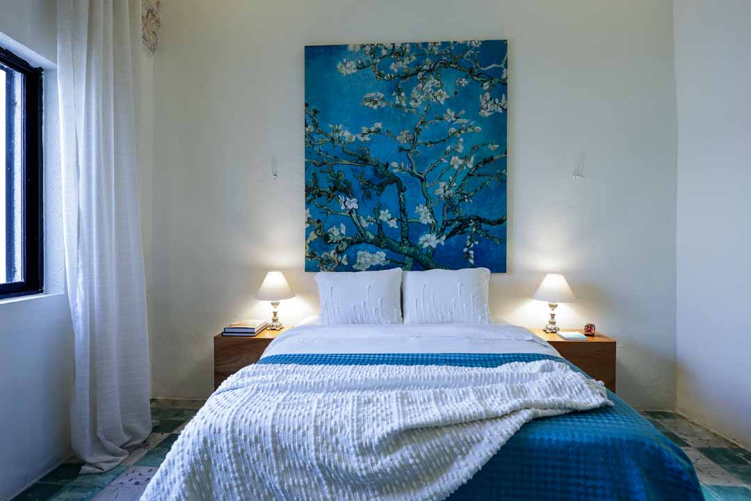 Cozy bedroom with blue accents and floral artwork.