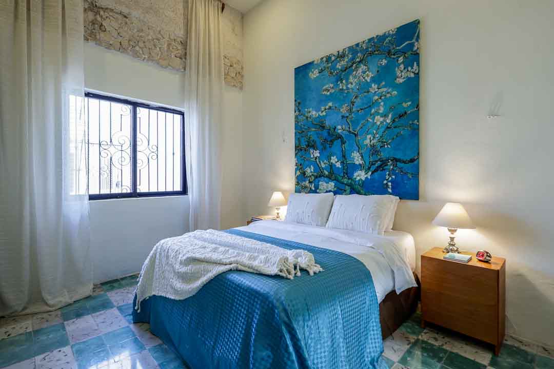 Cozy bedroom with blue and white bedding and floral wall art.