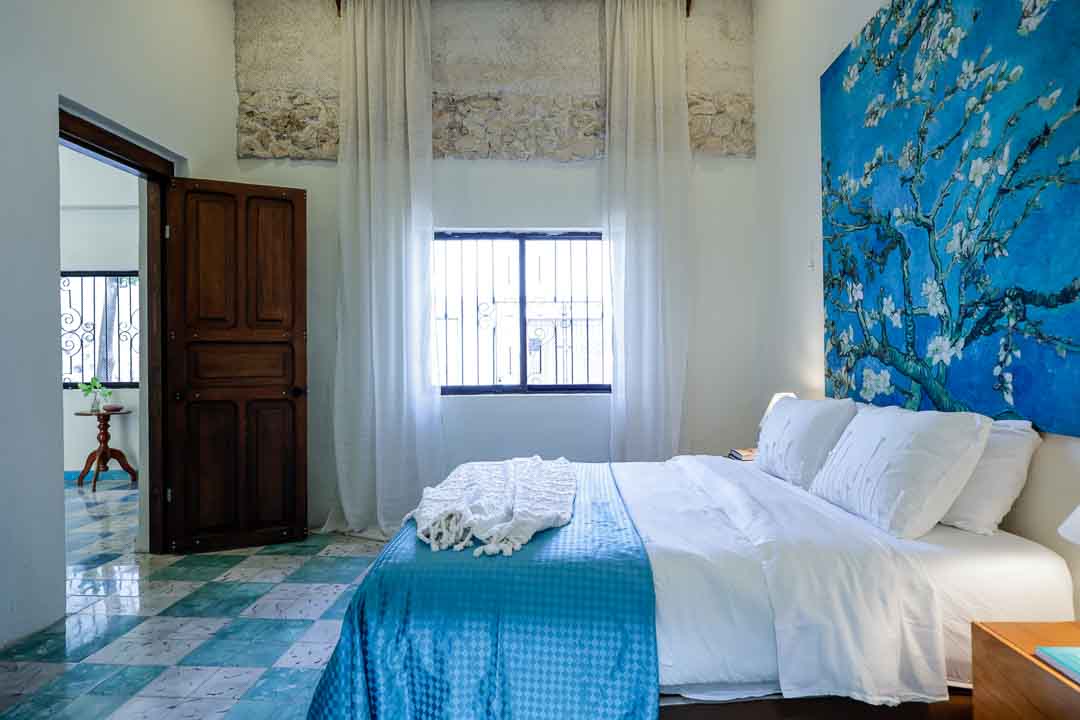 Bright bedroom with blue accents and natural light from a window.