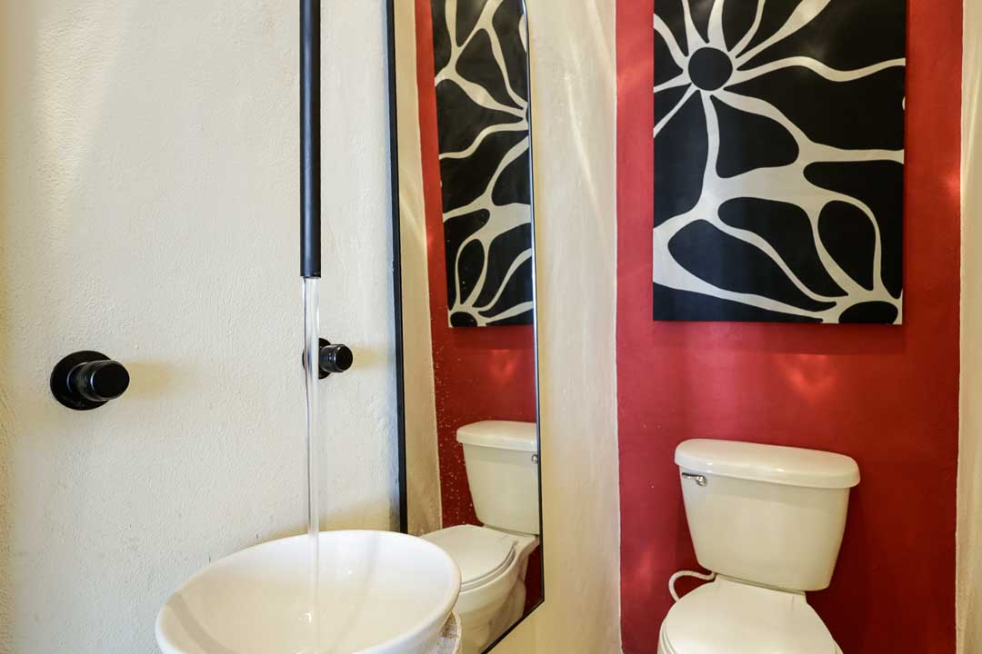 Small bathroom with red walls, white sink, and toilet.