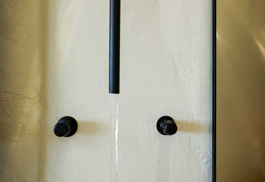 Two black knobs on a white door with a vertical black strip in the center.