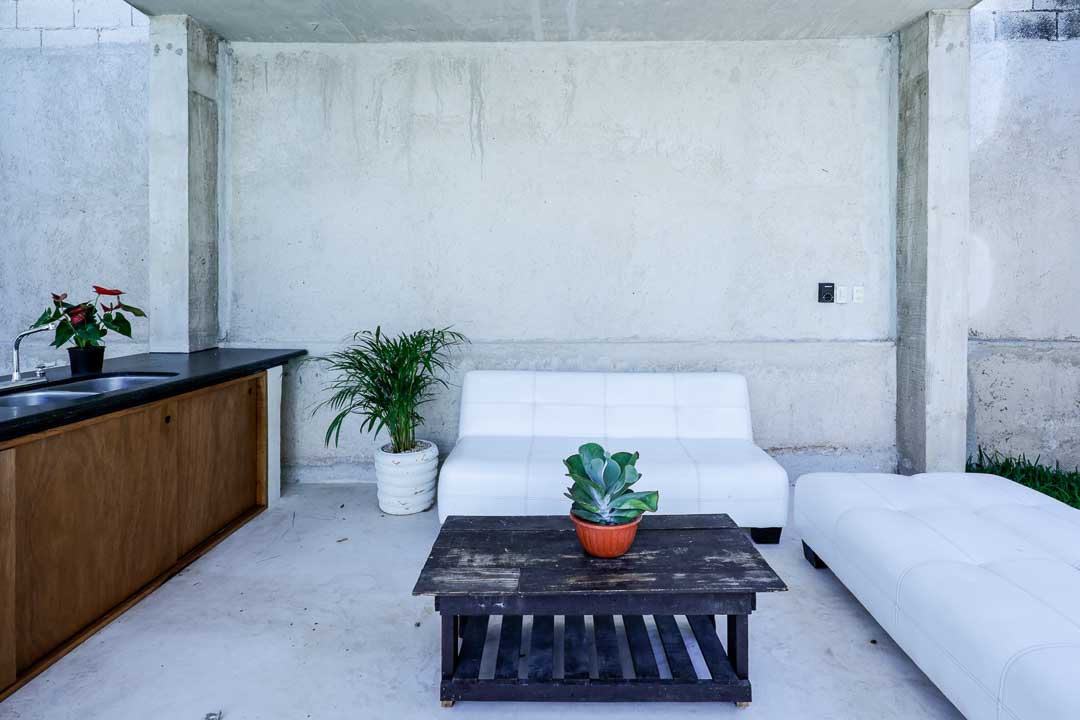 Minimalist outdoor seating area with white sofa and plants.