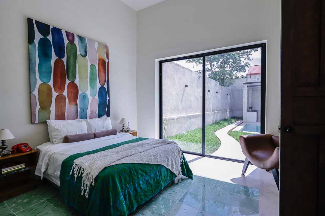 Modern bedroom with colorful artwork and sliding glass doors to a garden.