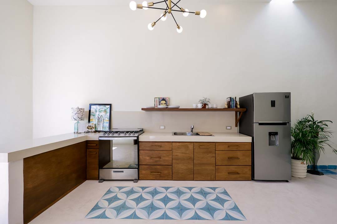 Modern kitchen with wooden cabinets, a geometric rug, and stainless steel appliances.