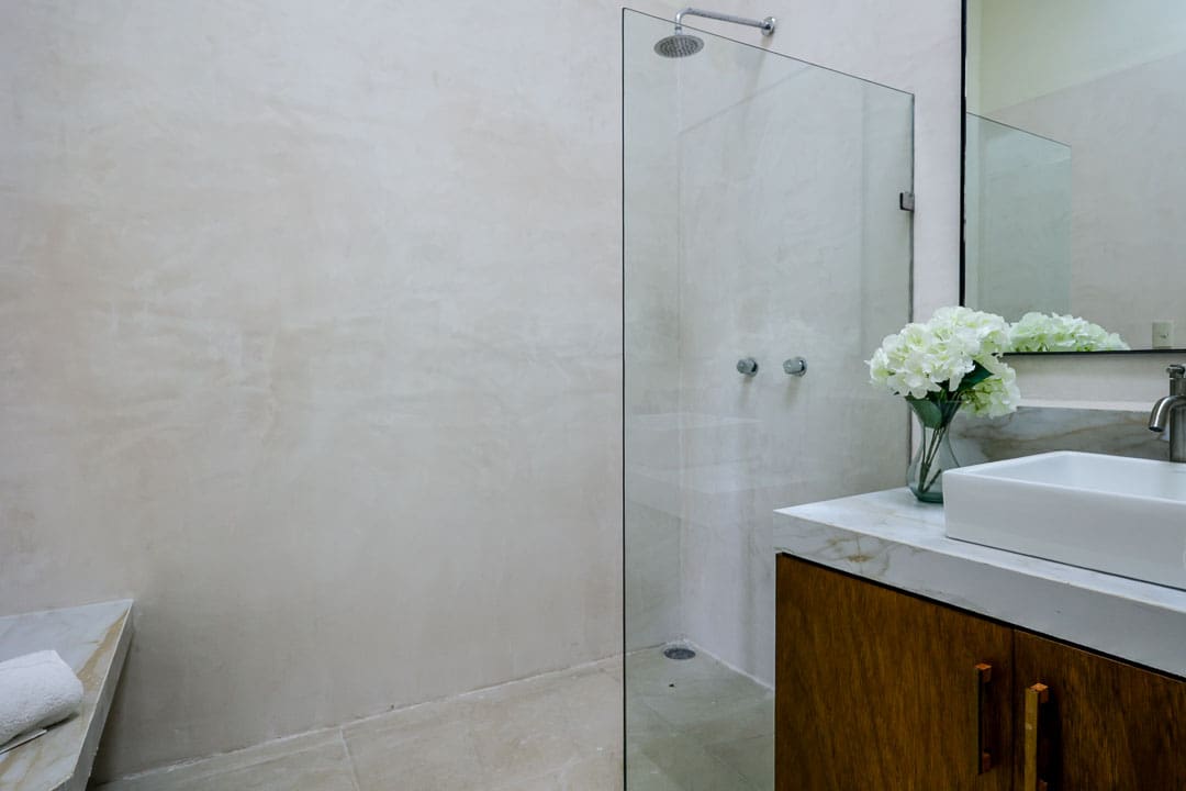 Minimalist bathroom with glass shower and wooden vanity.