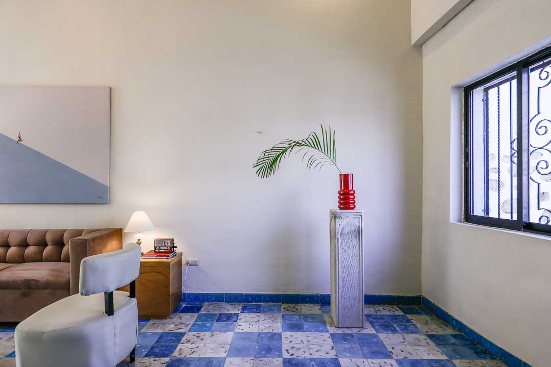 Minimalist room with blue checkered floor and a plant on a tall pedestal.