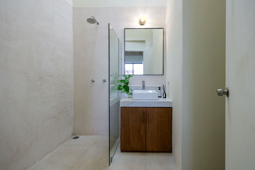 Minimalist bathroom with wooden vanity and glass shower partition.