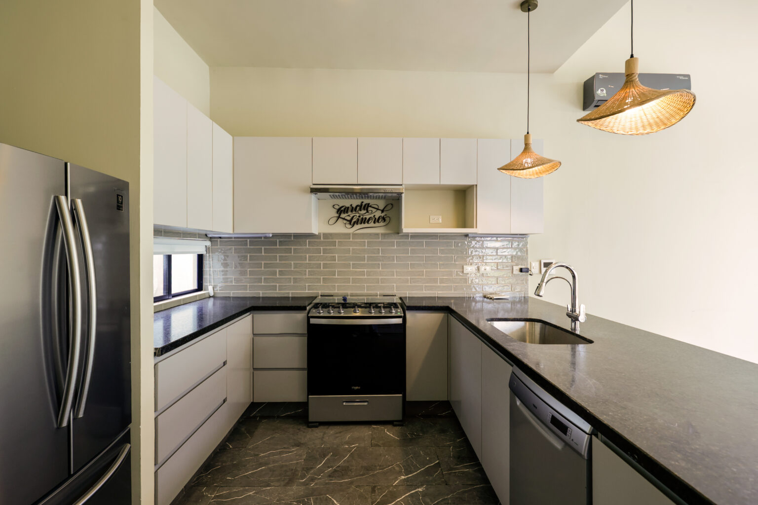 Modern kitchen with white cabinets and black appliances.