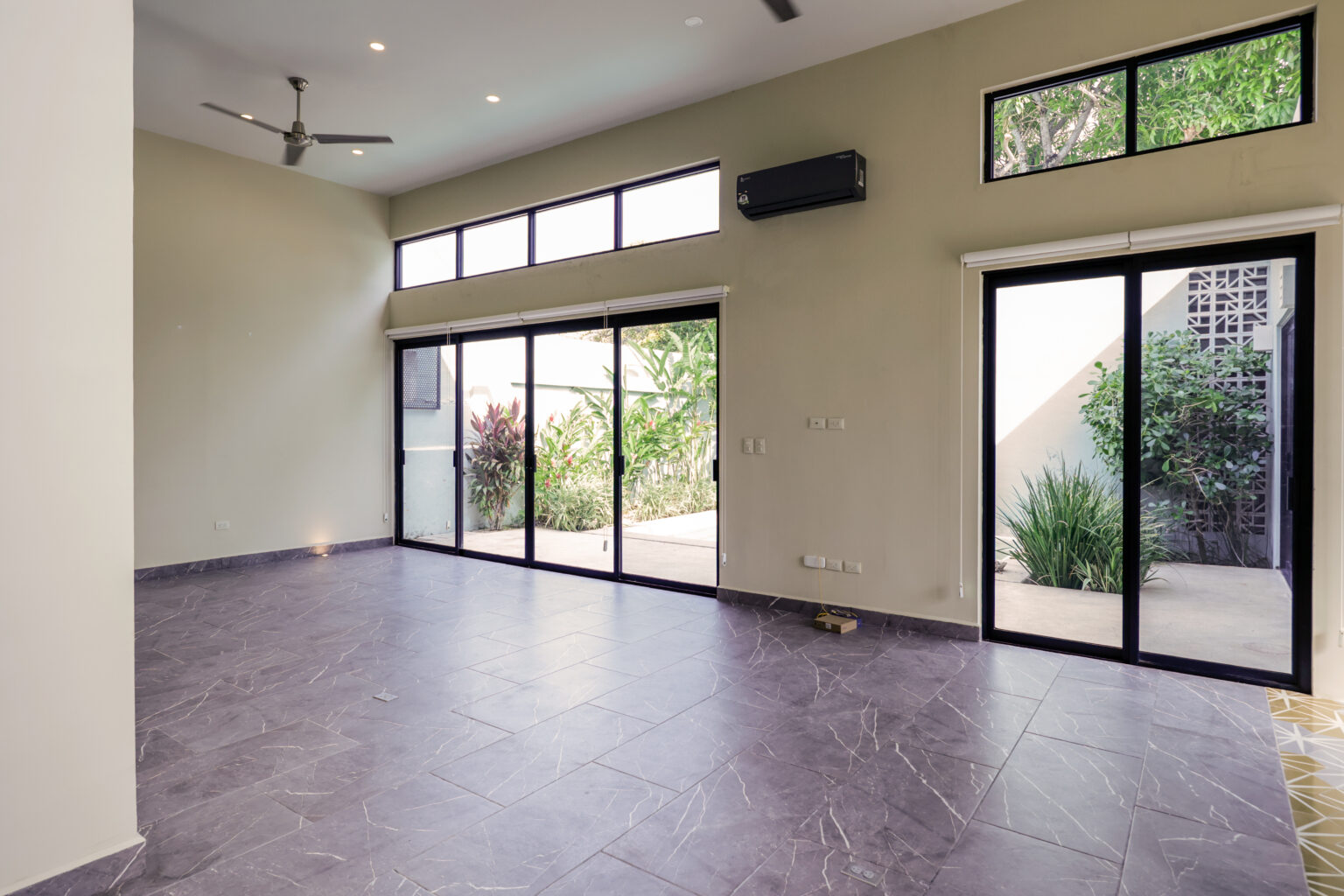 Empty modern room with large windows and tiled floor.