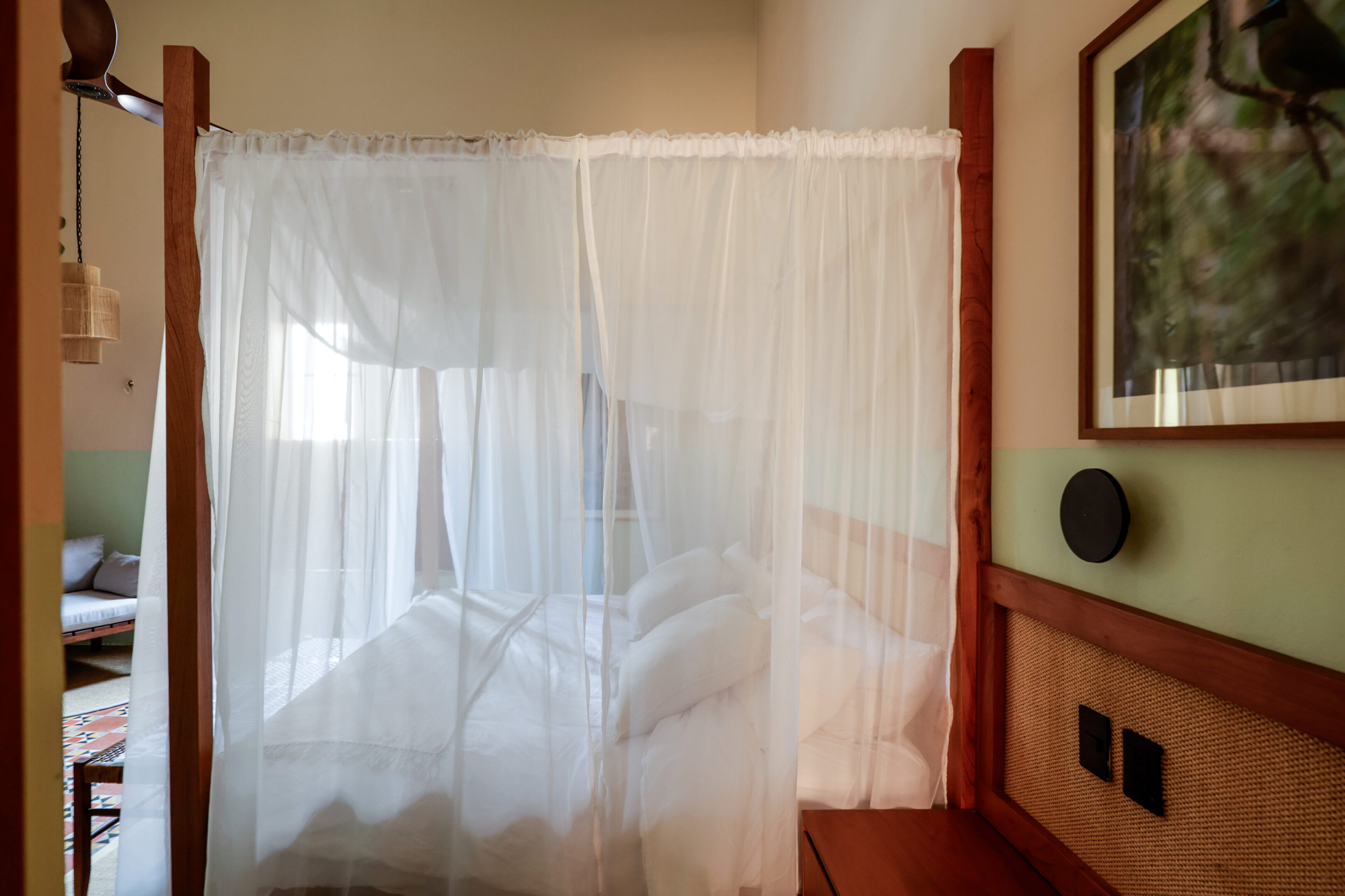Cozy bed surrounded by a white mosquito net in a warmly lit room.