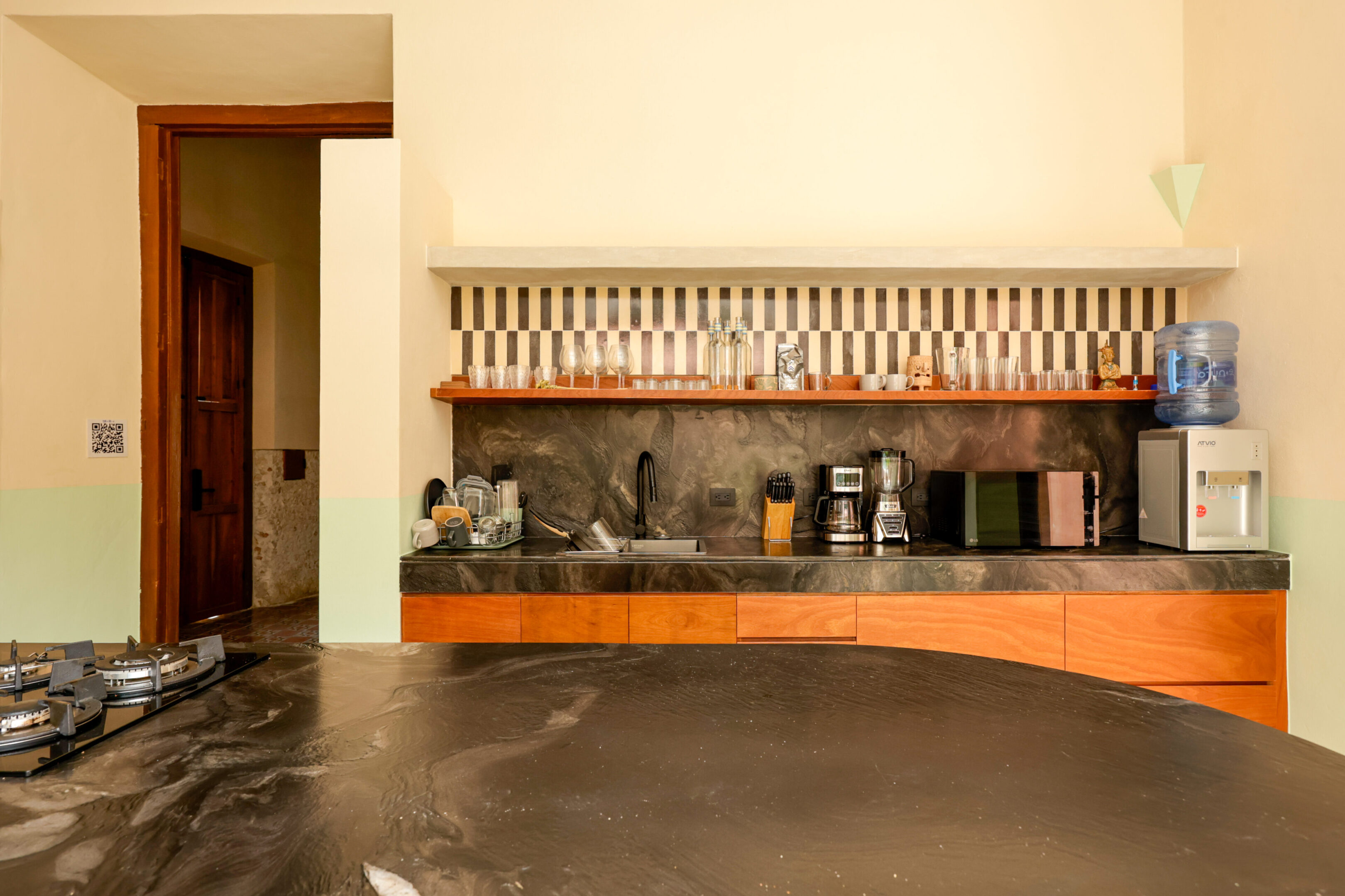 Modern kitchen with orange cabinets and hanging cups above the counter.