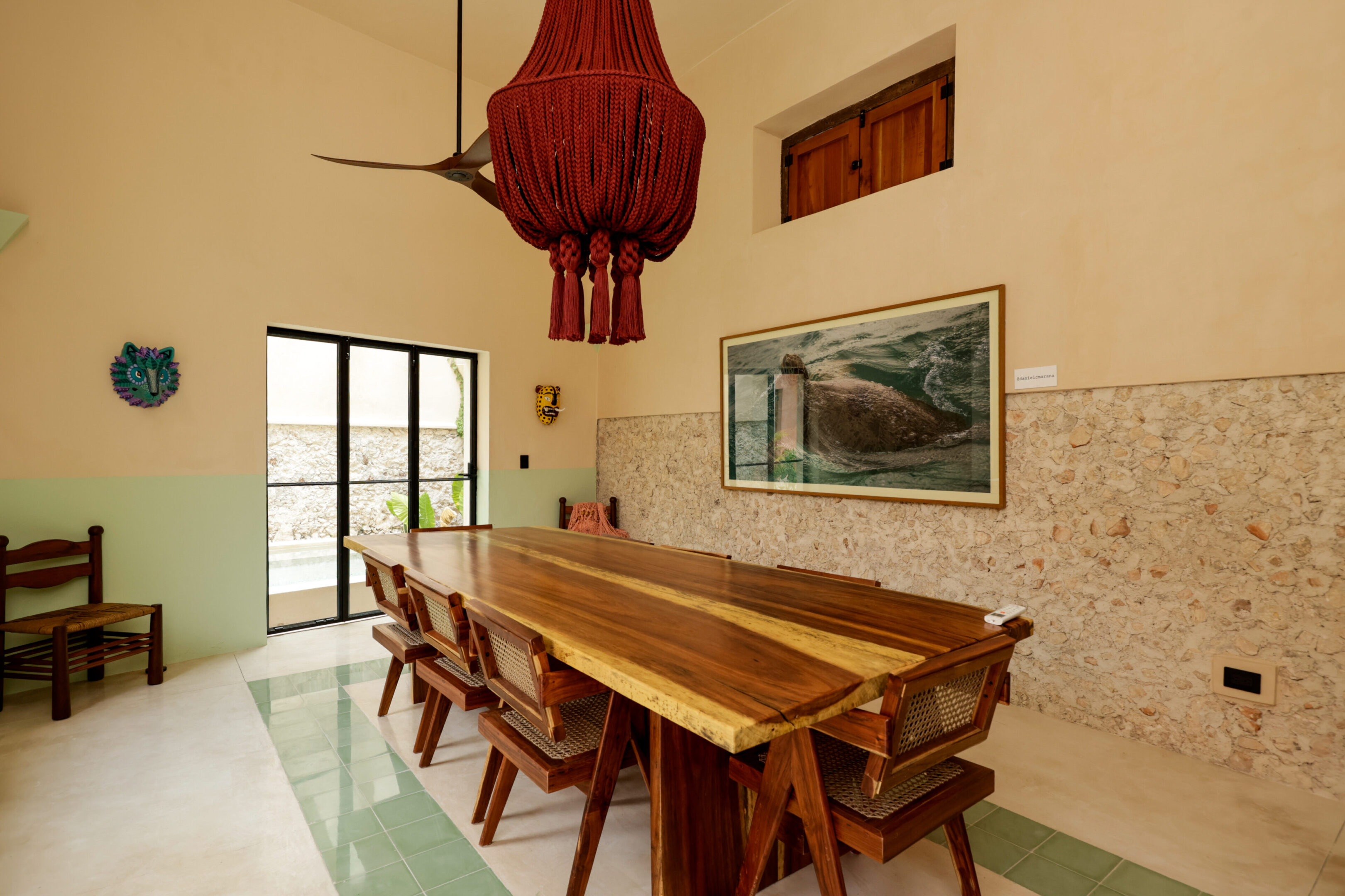 Rustic dining room with a large wooden table and unique red chandelier.
