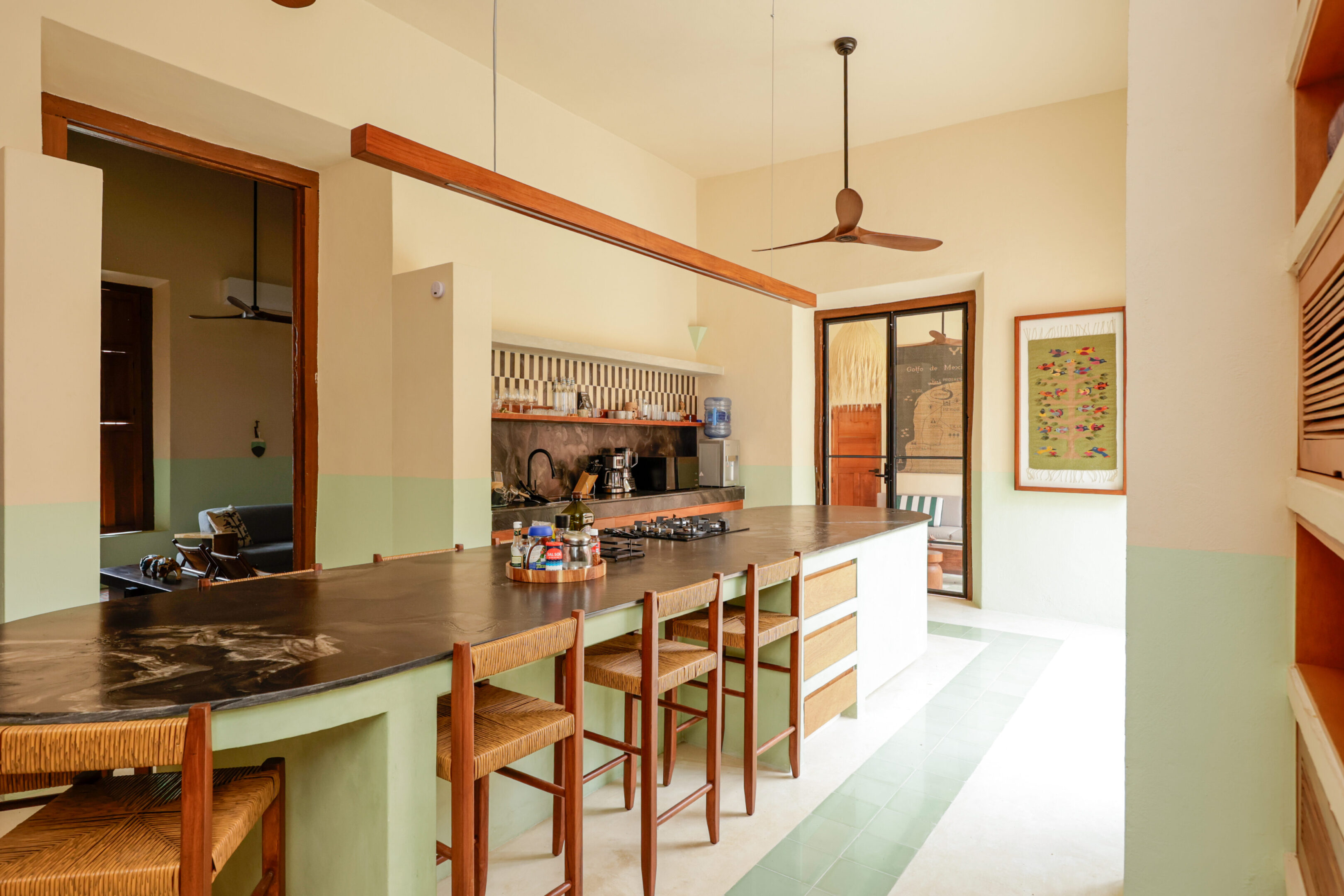 Bright kitchen with wooden bar stools and ceiling fan.