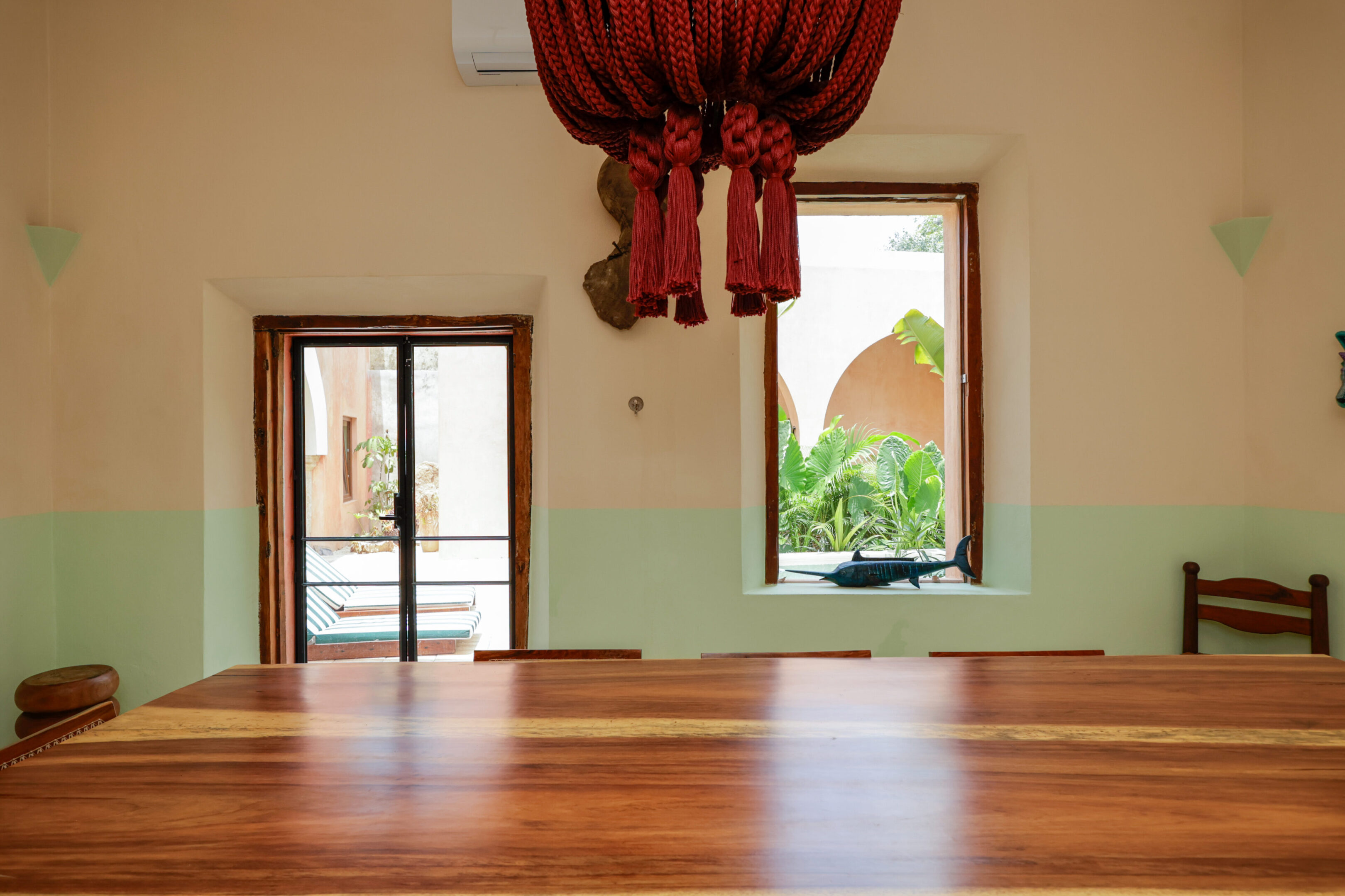 Empty room with wooden floor and large windows showing greenery outside.