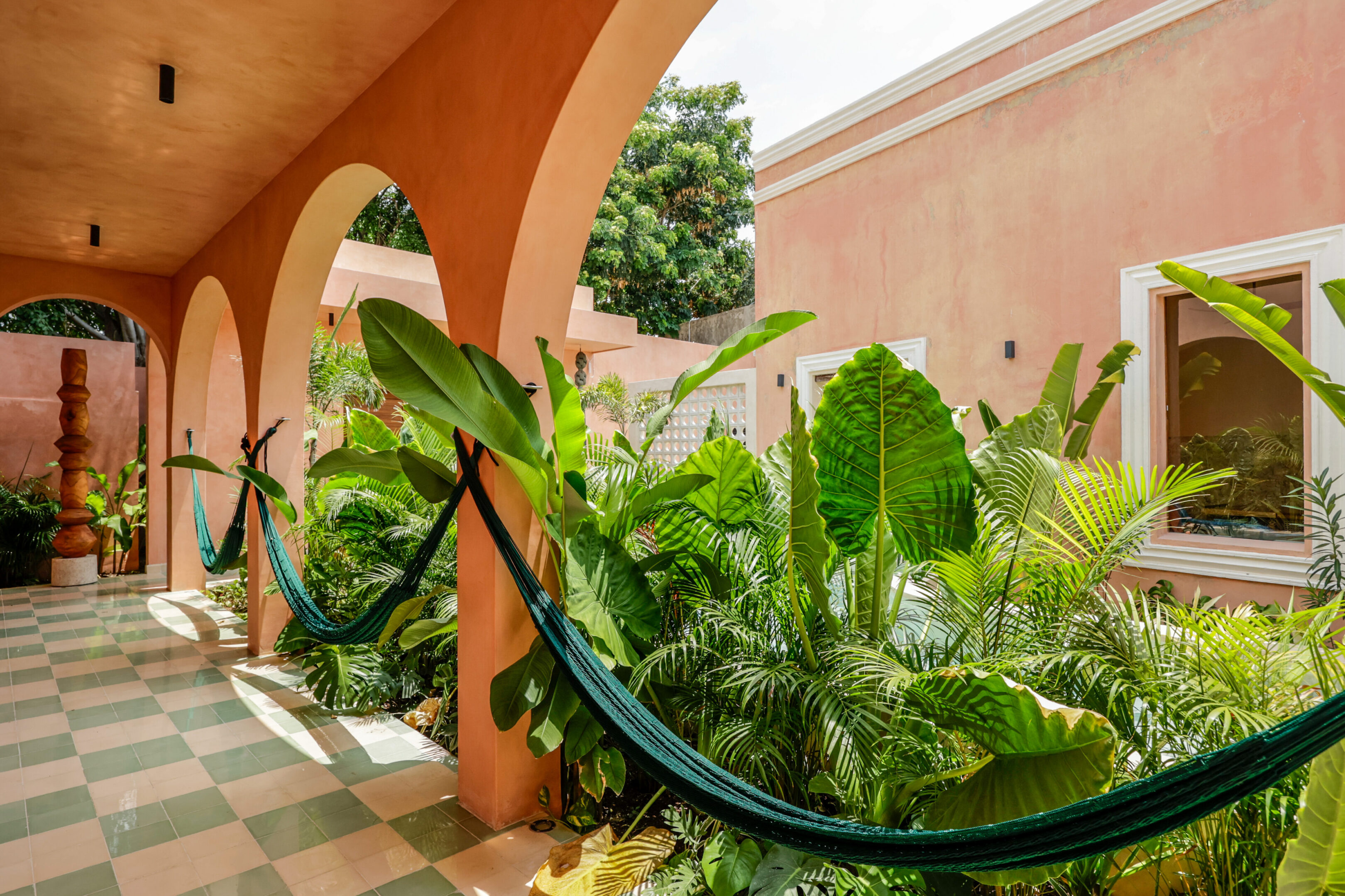 A hammock hangs peacefully among lush tropical plants under an arched terrace.
