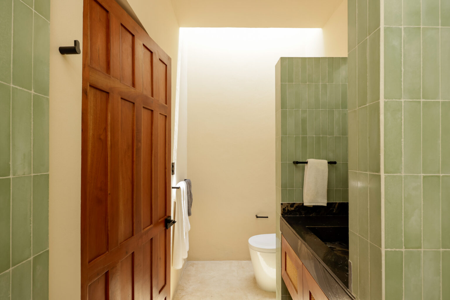 Minimalist bathroom with wooden door and stone countertop.