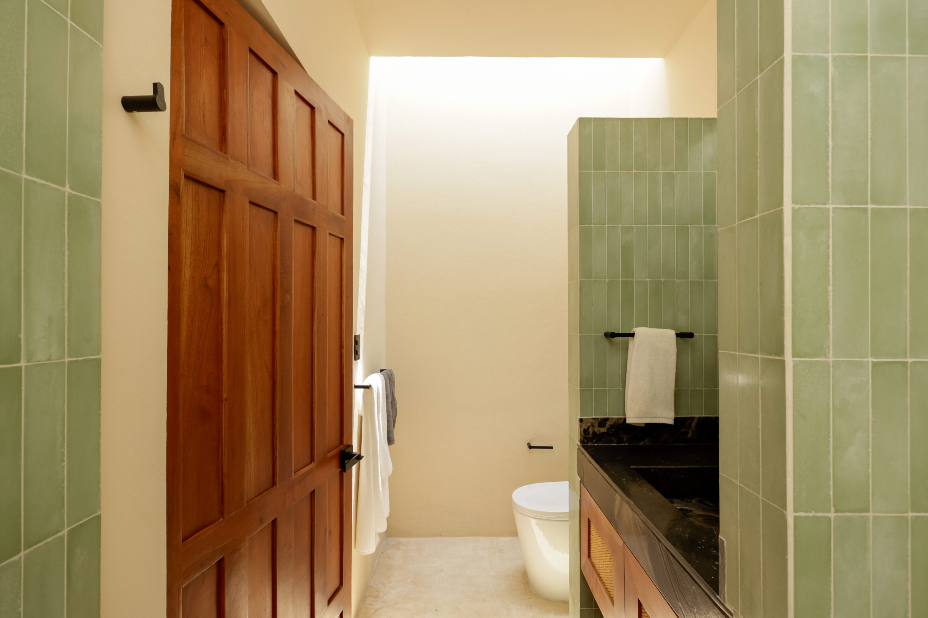 Minimalist bathroom with wooden door and stone countertop.